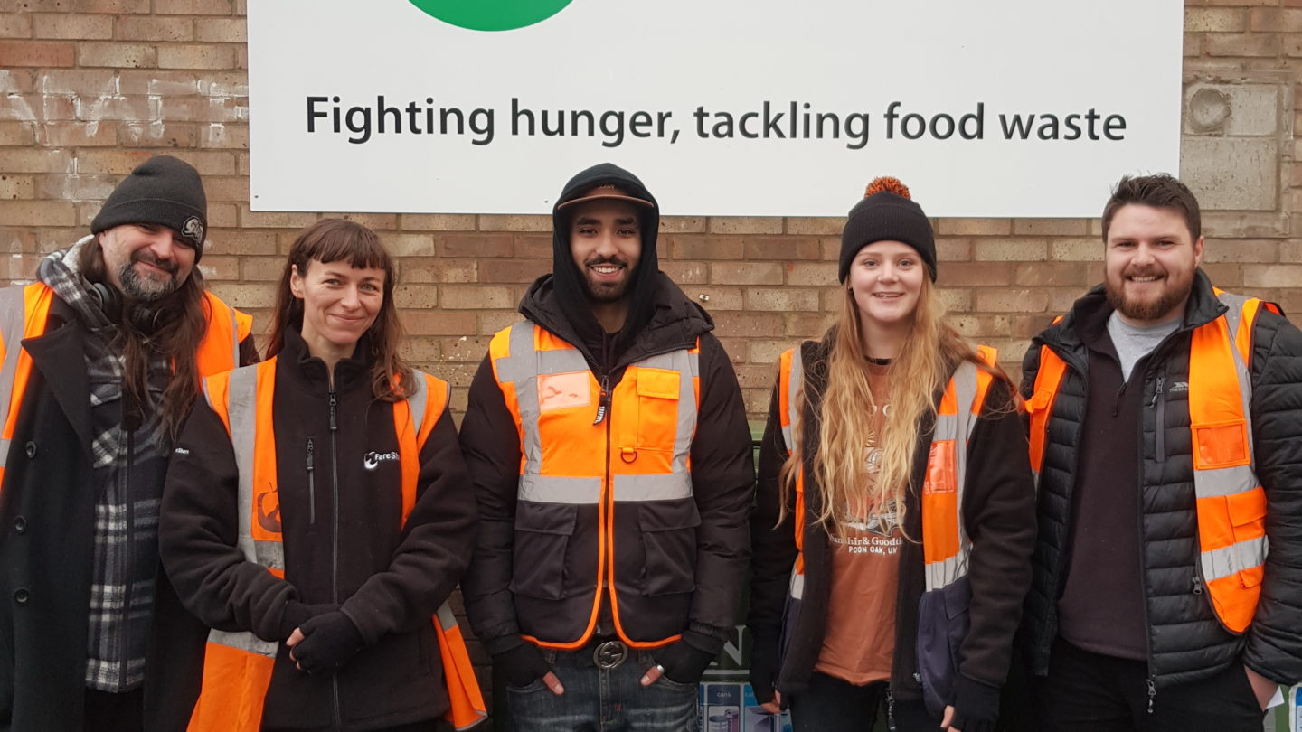 Group of employees from FareShare South West standing outside their south bristol warehouse smiling and looking at the camera.