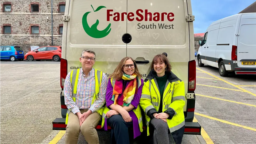 Pictured: Julian Mines, CEO Bristol Charities; Helen Godwin, WECA Mayor; Josie Forsyth, DCEO FareShare South West. Three people are sitting on the tailgate of a FareShare South West van, smiling.