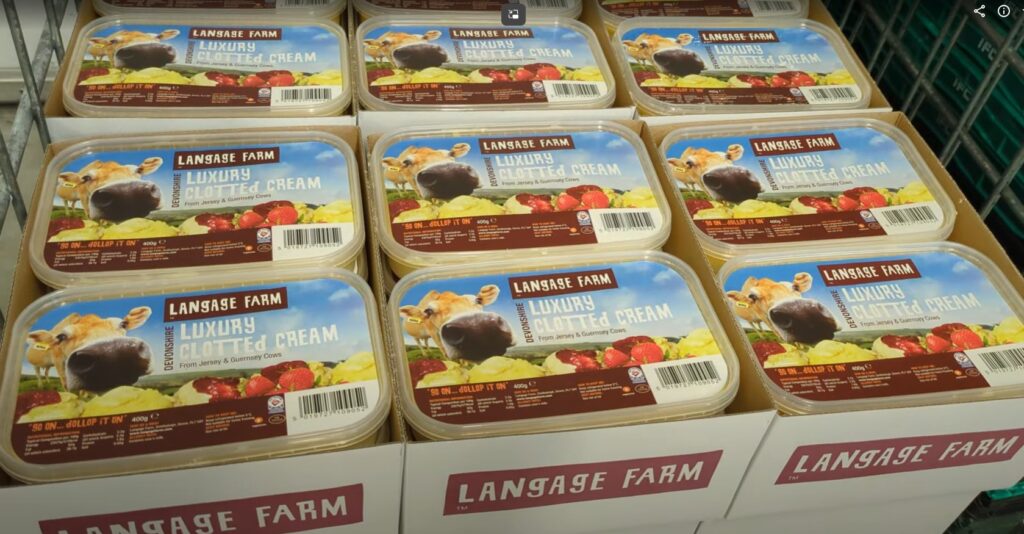 Cardboard box full of tubs of Langage Farm luxury clotted cream. Each tub has a photo of the head of a Jersey cow on